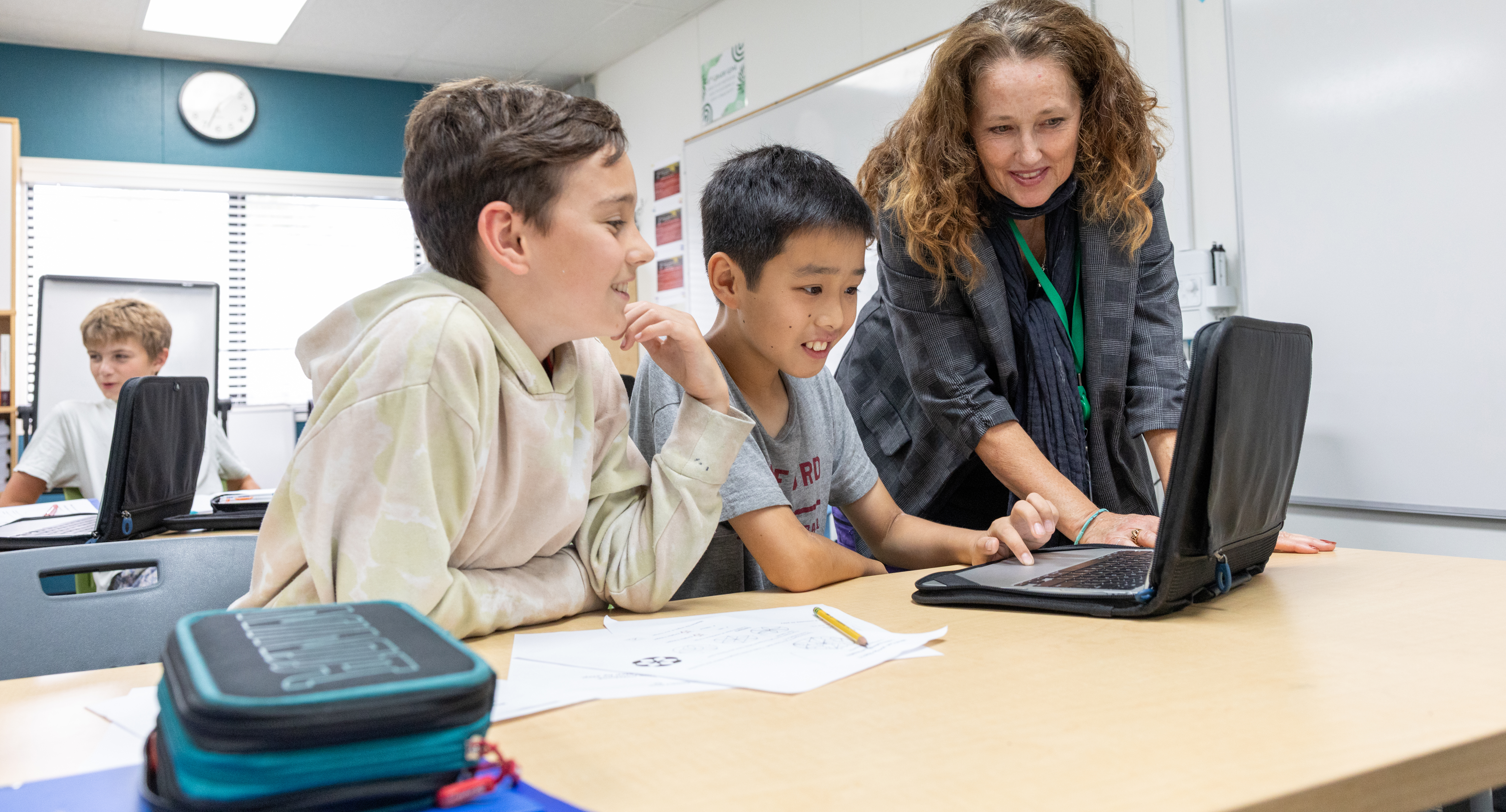 Middle school teacher with two students working on a computer